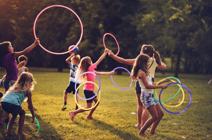 Kinder spielen mit bunten Ringen. Es zeigt die spielerische Art des Body'n brain Coachings, das Rahel durchführt.